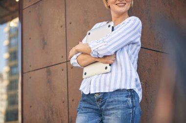 Duvara yaslanmış defterli bir kadın.