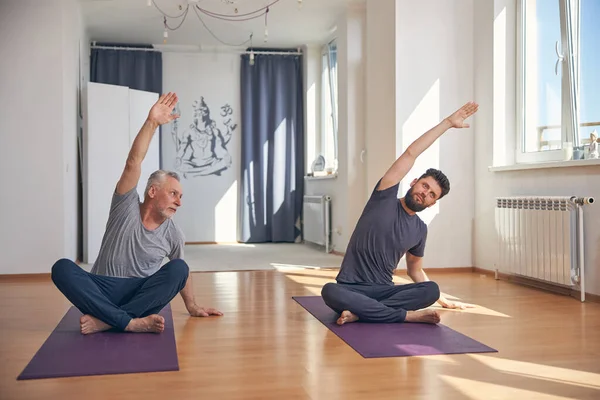 Profesyonel yoga hocası öğrencisiyle esneme hareketleri yapıyor. — Stok fotoğraf