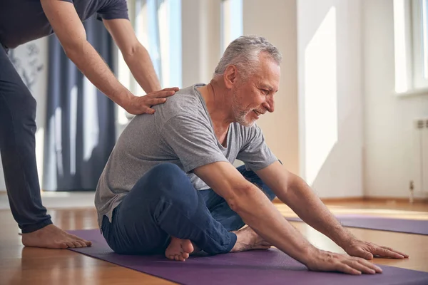 Maschio sorridente che esegue un esercizio di yoga seduto di base — Foto Stock