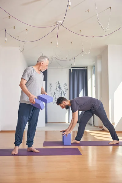 Ciddi koyu renk saçlı koç acemi bir yogiyi yönlendiriyor. — Stok fotoğraf