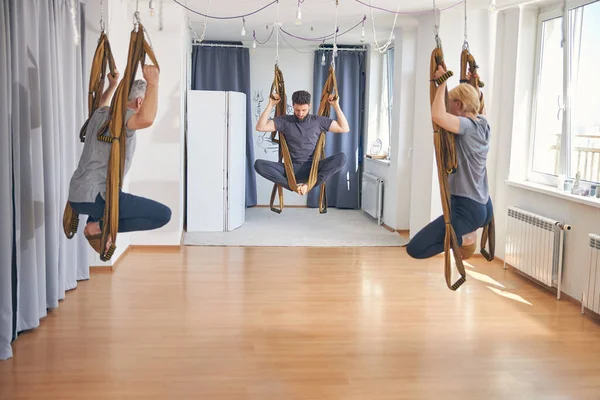 Três iogues aptos fazendo ioga aérea juntos — Fotografia de Stock