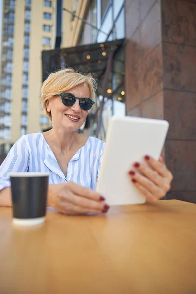 Femme élégante et souriante assise dans un café — Photo