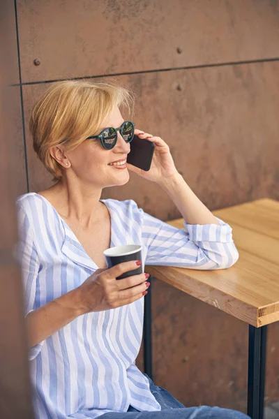 Donna a un tavolo che fa una conversazione telefonica — Foto Stock