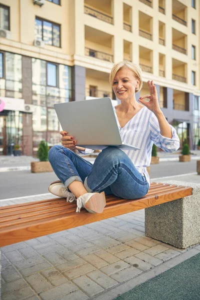 Joyeux dame assis jambes croisées sur le banc — Photo