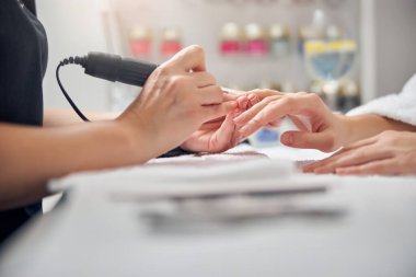 Güzellik uzmanı ofiste çalışan bir kadın için manikür yapıyor.