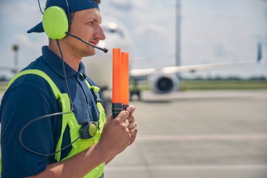 Sinyal veren adam önünde asalar tutuyor.