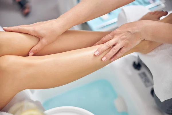 Estetista facendo massaggio per le gambe femminili con le mani — Foto Stock