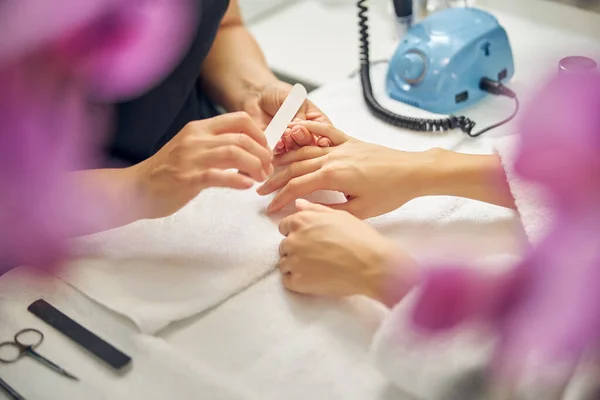 Woman having nails filed by professional in salon — Stock Photo, Image