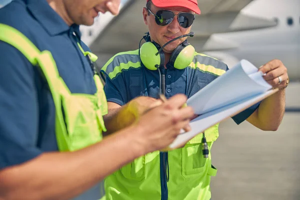Focused airport worker signing a document outdoors