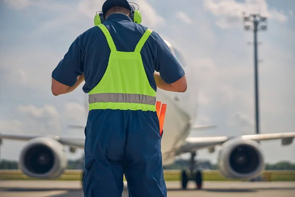 Airport worker in uniform meeting a plane — Stock Photo, Image
