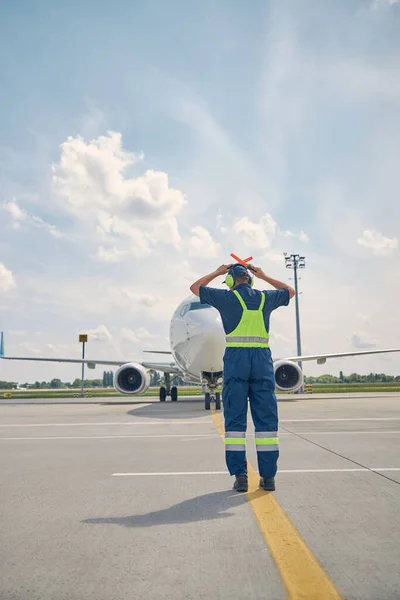 Caucasian male airport worker signaling the pilot — Stock Photo, Image