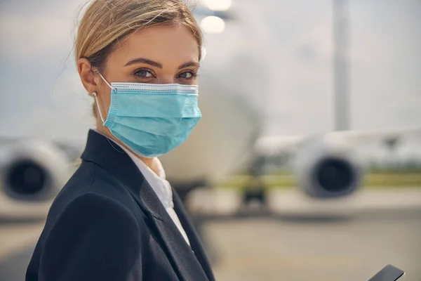 Blonde woman with a gadget standing outside