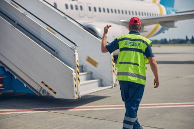 Havalimanında bir araç operatörüne rehberlik ediyor.