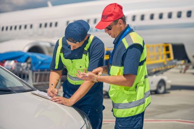 Odaklanmış beyaz adam arabanın kaputuna yazı yazıyor.