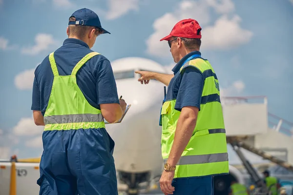 Kompetenta flygplatsarbetare som utför en inspektion efter flygning — Stockfoto