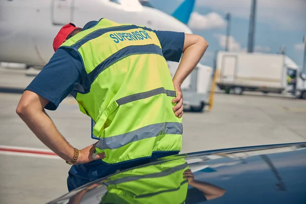 Lotnisko mężczyzna pracownik zgięty podwójnie od ostrego bólu — Zdjęcie stockowe