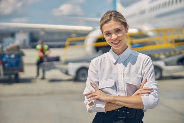 Sonriendo elegante empleado de la aerolínea está de pie al aire libre — Foto de Stock