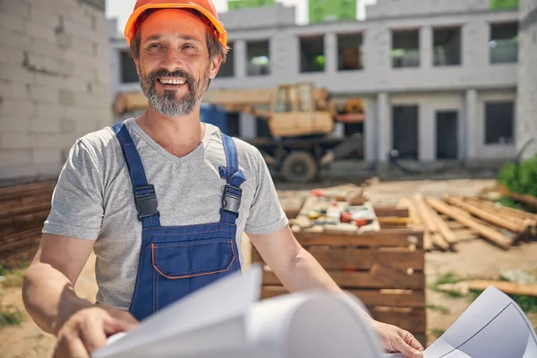 Een man met een harde hoed met een huisplan. — Stockfoto