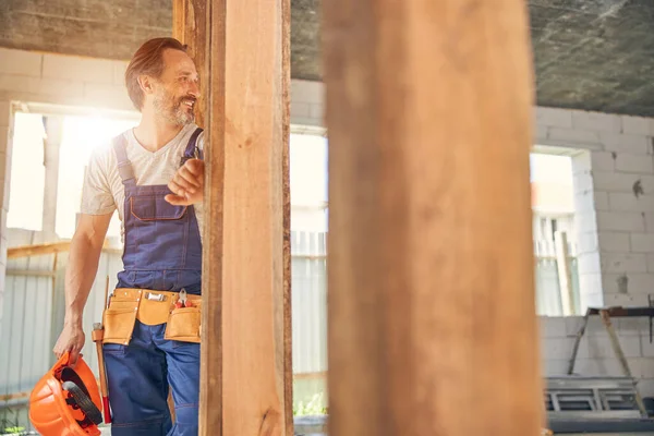 Constructor sonriente de pie en una casa a medio terminar — Foto de Stock