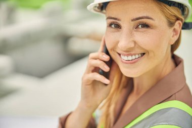 Elinde bir aletle kameraya gülümseyen kadın mühendis.