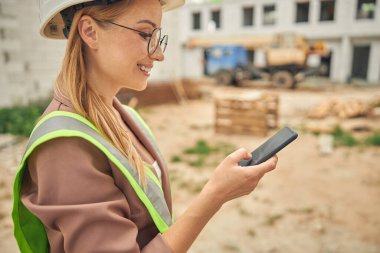 Dışarıda aletini kullanan memnun genç bir kadın.