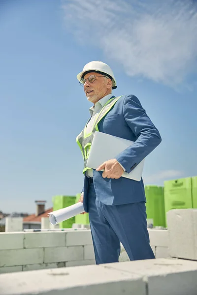 Homem com um capacete segurando um rolo de papel — Fotografia de Stock