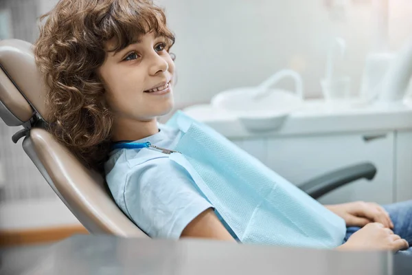 Wesołe dziecko na fotelu dentystycznym czeka na dentystę — Zdjęcie stockowe
