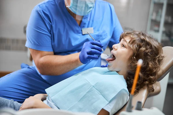 Wesoły dzieciak siedzący na fotelu dentystycznym podczas kontroli — Zdjęcie stockowe