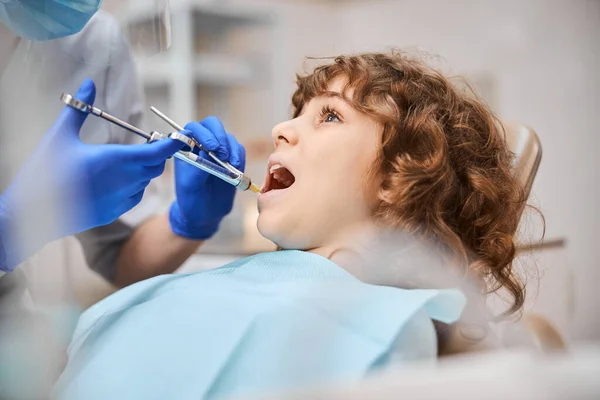 Niño en silla dental recibiendo anestesia en la clínica — Foto de Stock