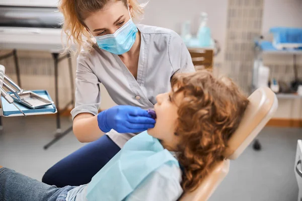 Tandläkare sätter en bit block i barnmun på kliniken — Stockfoto