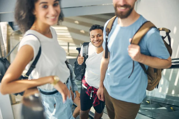 Viajantes sorridentes felizes na escadaria em movimento no aeroporto — Fotografia de Stock