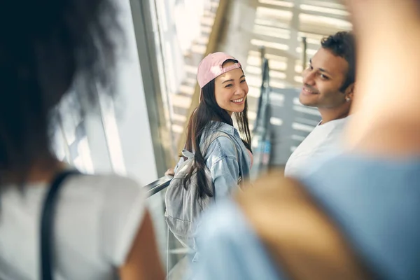 Χαμογελώντας θηλυκό και αρσενικό σε μια κινούμενη σκάλα στο αεροδρόμιο για να πιάσει μια πτήση — Φωτογραφία Αρχείου