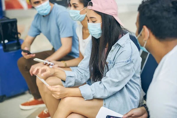 他の人の近くに座っている間、携帯電話を使用して保護マスクのアジアの女性 — ストック写真