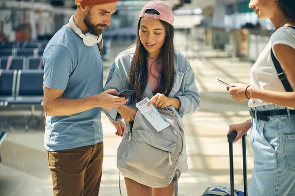 Asyalı kadın, adamın yanında biniş kartı alıyor.