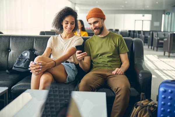 Hombre guapo sentado en el sofá negro en el departamento de espera en el aeropuerto — Foto de Stock