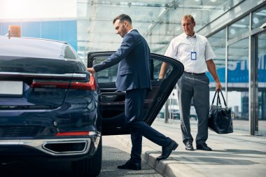 Güzel takım elbiseli bir adam havaalanından işe gidip gelmek için araba açıyor.