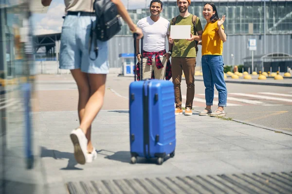 Mujer con maleta azul yendo a su grupo de turistas —  Fotos de Stock