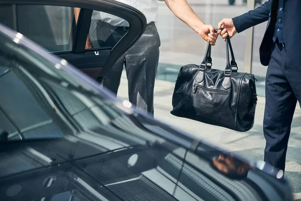 Taxi driver passing a duffel bag to a passenger — Stock Photo, Image