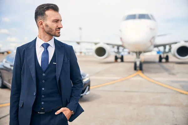 Młody biznesmen pozujący przed samolotem — Zdjęcie stockowe