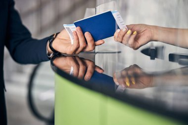Resepsiyoniste pasaport ve bilet gösteren bir yolcu.