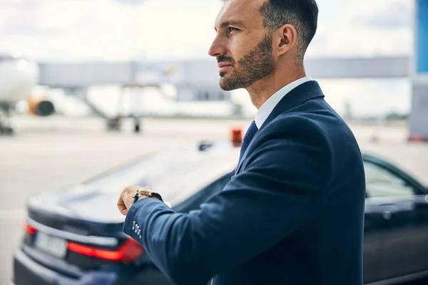 Elegant man lifting his left hand to check the time — Stock Photo, Image