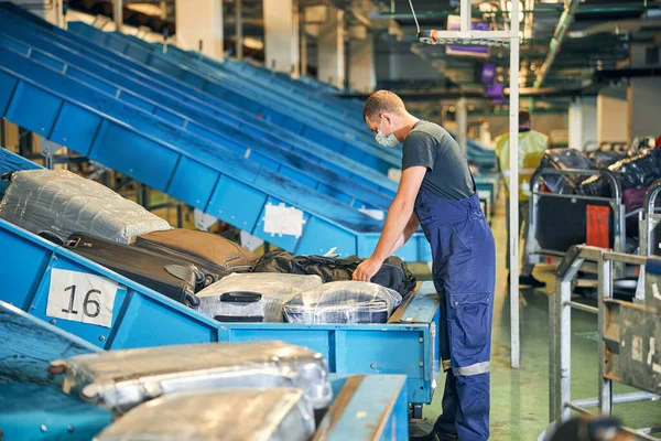 Baggage handler checking a suitcase in the sorting room — Stock Photo, Image