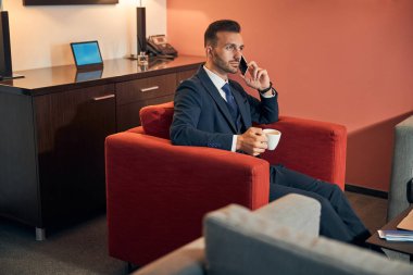 Sakin bir girişimci otel odasında telefonla konuşuyor.