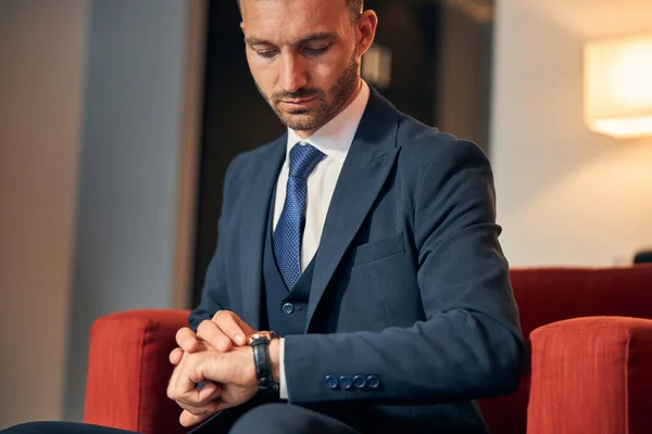Spokojny przedsiębiorca czeka i patrzy na zegarek — Zdjęcie stockowe