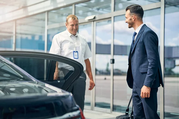 Autista allegro incontro amichevole uomo d'affari in aeroporto — Foto Stock