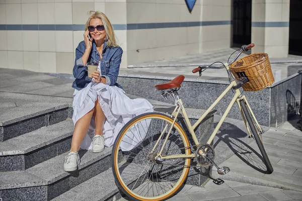 유행적 인 성인 여성이 현대 건물 앞에서 휴대 전화로 이야기하는 모습 — 스톡 사진