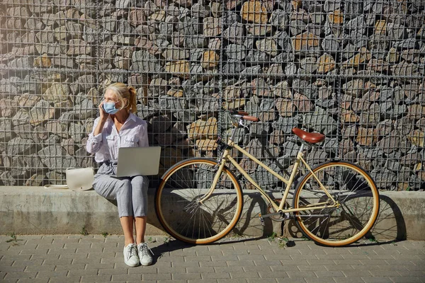실내에서 랩탑과 자전거로 보호용 마스크를 쓰고 있는 여자 — 스톡 사진