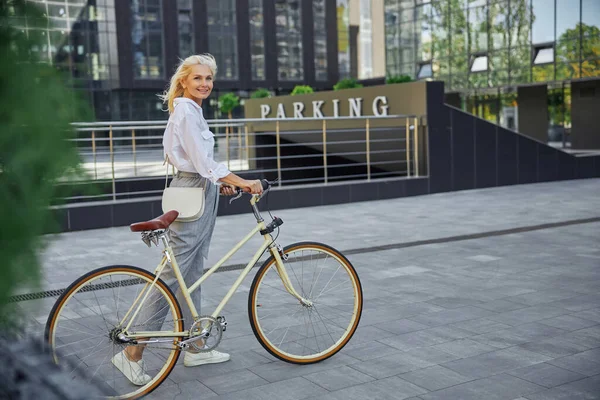 站在地下停车场前骑自行车的金发成年女子 — 图库照片