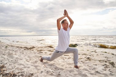 Huzurlu adam sabahları plajda yoga yapıyor.