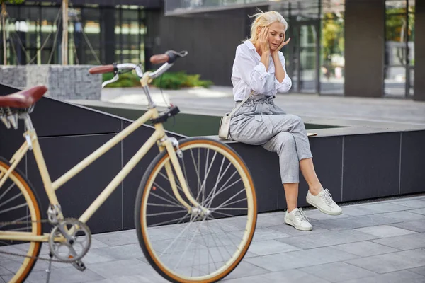 Kadın şu anda gözlerini kapatırken iki eline de dokunuyor.
